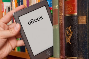 eBook vs Buch, e-Reader aus einem Bücherregal ziehen